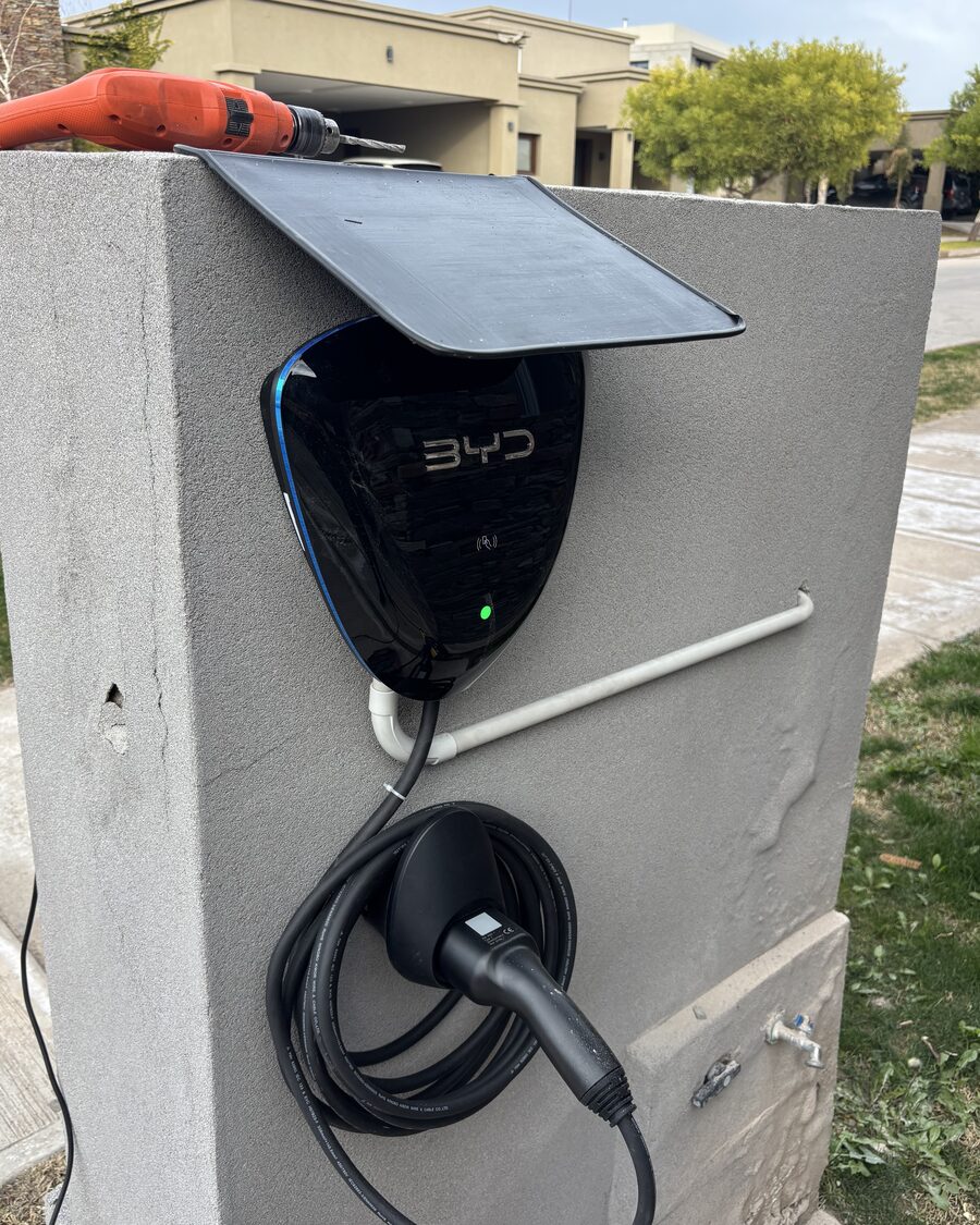Instalación en curso de un cargador BYD sobre un pilar, con visera de protección