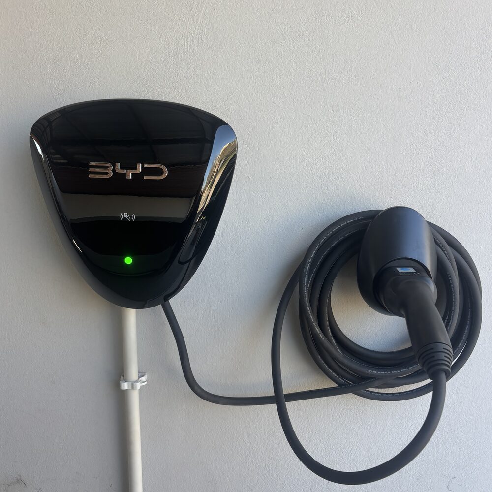 Cargador residencial BYD montado en la pared, con el cable enrollado